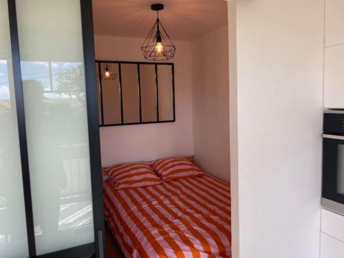 - une petite chambre avec un lit et une couverture rayée dans l'établissement Appartement en centre-ville, à La Teste-de-Buch