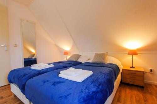 a bedroom with two beds with blue sheets and two lamps at Resort Klein Giethoorn - Vakantiewoning 25 in Opperdoes