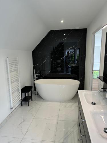 La salle de bains est pourvue d'une grande baignoire et d'un mur noir. dans l'établissement VILLA BENODET 4 Etoiles, à Bénodet