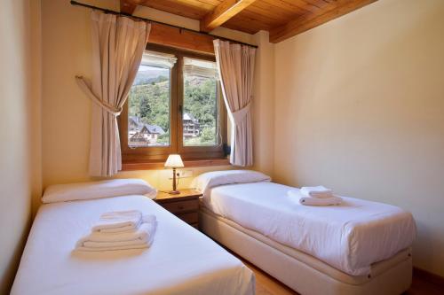 2 camas en una habitación con ventana en Luderna - Apartamento Dera Pincèla, en Vielha