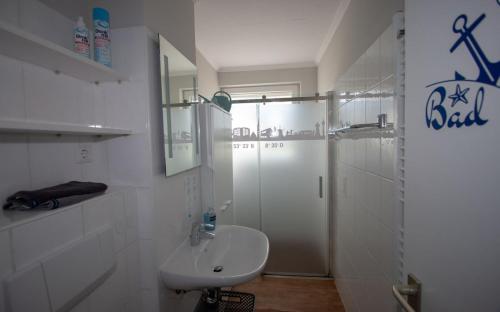 a white bathroom with a sink and a shower at Ferienwohnung Breitschuhs Havenwelten Bremerhaven in Bremerhaven