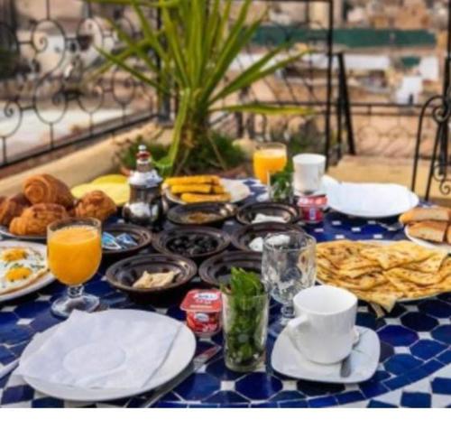 una mesa azul y blanca con desayuno y bebidas en Riad lala Drissia, en Fez