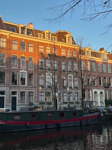 a large building next to a river with a boat at Prinsengracht Hotel in Amsterdam