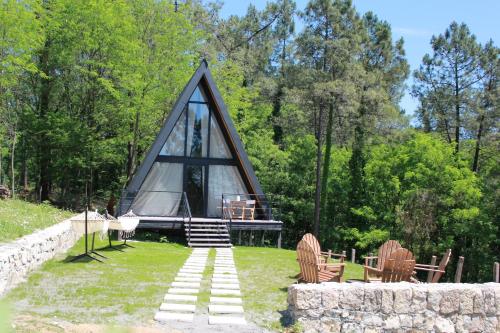a cabin in the middle of a field with chairs and trees at Vintage Cabin in Kutaisi