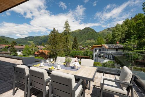 a table and chairs on a patio with mountains in the background at Penthouse Bergseetraum mit 102 qm Dachterrasse in Walchsee