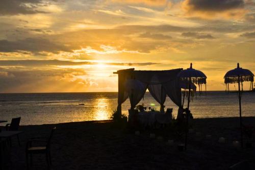 a wedding on the beach with the sunset in the background at Siena 1 BR Superior Garden Room JU23 in Mataram