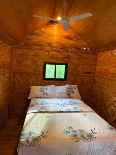 a bed in a small room with a ceiling fan at Rose Cabins Bohol in Loon