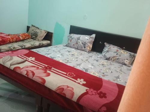 a bed with a red and white blanket on it at KC Hotel & Restaurant in Rudraprayāg