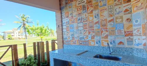 Casa Térrea - Villa das Águas - Praia do Saco في بلدية إيستانكيا: حمام مع مغسلة وجدار مع ملصقات