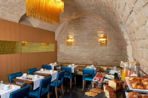 a restaurant with tables and blue chairs and bread at Hotel Opéra Richepanse in Paris