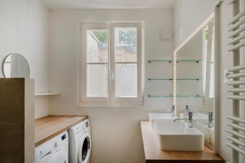 La salle de bains blanche est pourvue d'un lavabo et d'un lave-linge. dans l'établissement Paris Porte Maillot Design Residence, à Neuilly-sur-Seine