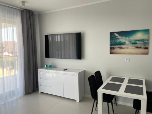 a white room with a white desk and a white dresser at Apartamenty AQUA MAZURY in Ełk