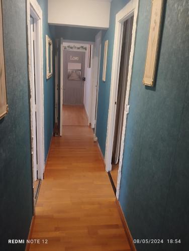 - un couloir dans une maison dotée de murs bleus et de parquet dans l'établissement positano, à Lardy