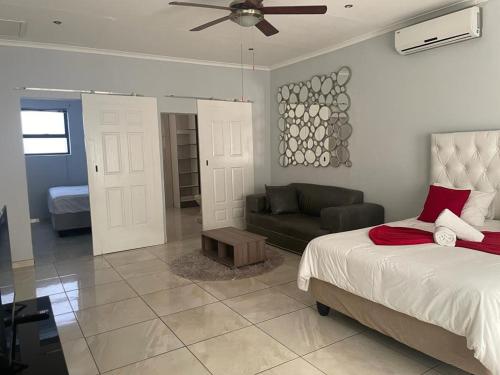 een slaapkamer met een bed, een bank en een plafondventilator bij Angelshof Self Catering Guesthouse in Windhoek