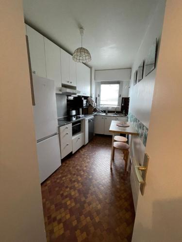 une cuisine avec des placards blancs et une table avec une chaise dans l'établissement Sympa-Appart, à Paris