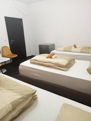 a room with three beds and a chair at Rezidencija Arion in Kraljevo