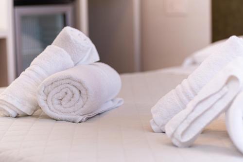 a roll of white towels sitting on a bed at Gallo's City Rooms in Termoli
