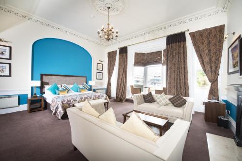 a bedroom with a bed and a couch and chairs at Columba Hotel Inverness by Compass Hospitality in Inverness