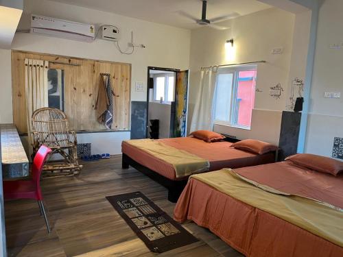 a room with two beds and a chair in it at NIRMAN HOMESTAY 5 minutes walk to beach in Puri