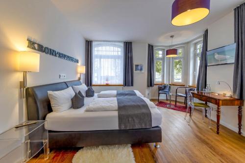 a bedroom with a large bed with a desk and a table at Designhotel 1690 & Apartments in Rendsburg