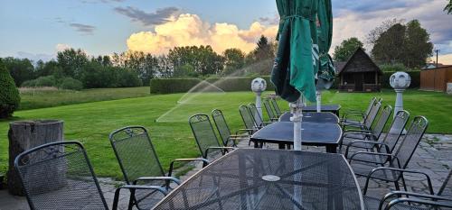 a group of tables and chairs with a green umbrella at U rybníka Smrčná in Nová Bystřice