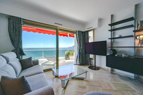 un salon avec un canapé et une grande fenêtre dans l'établissement 2-Br sea view private parking walk to beaches, à Cannes