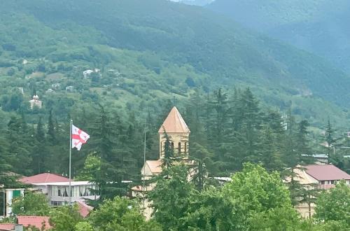 a building with a canadian flag in front of a mountain at Chateau Bagdati in Nerget'i