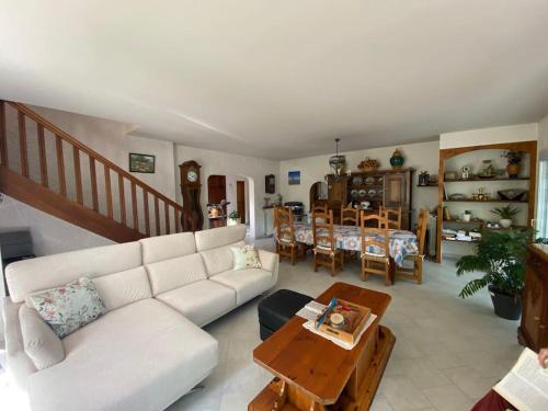 un salon avec un canapé blanc et une table dans l'établissement Maison familiale dans un grand jardin arboré, à Gujan-Mestras
