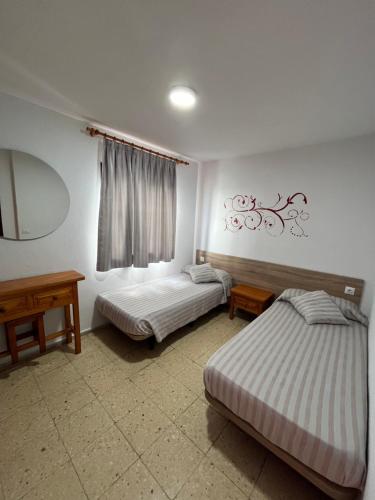 1 dormitorio con 2 camas, mesa y espejo en Apartamentos Buenavista en Puerto Rico