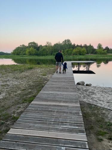 a man and a child walking down a wooden boardwalk at Relax nad Narwią u Oli I Pawła in Pultusk