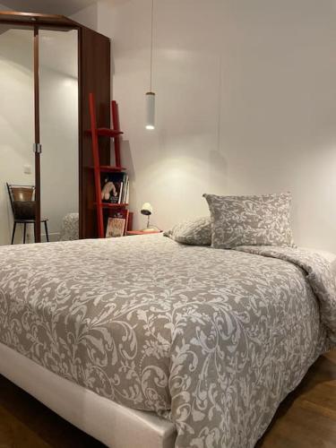 - une chambre avec un lit et une couette grise et blanche dans l'établissement Charmant 2 pieces Parisien à 10 min de MONTMARTRE, à Paris