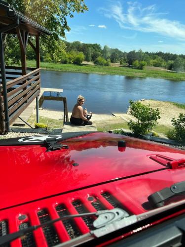 a person sitting next to a body of water at Relax nad Narwią u Oli I Pawła in Pultusk