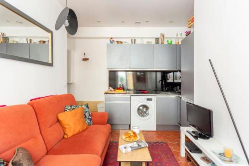 un salon avec un canapé orange et une cuisine dans l'établissement Charmant 2 pieces Parisien à 10 min de MONTMARTRE, à Paris