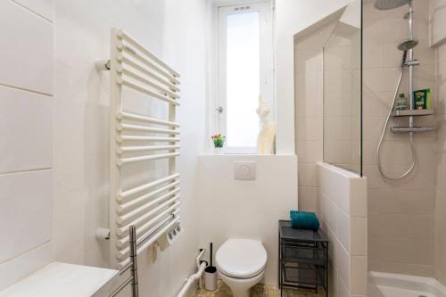 une salle de bain blanche avec toilettes et douche dans l'établissement Charmant 2 pieces Parisien à 10 min de MONTMARTRE, à Paris