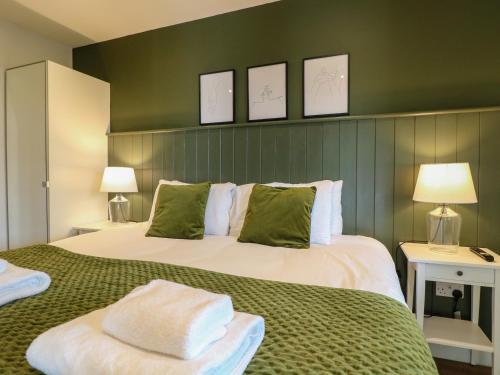 a bedroom with a large bed with green walls at The Wood Shed, Bank Top Farm in Ashbourne