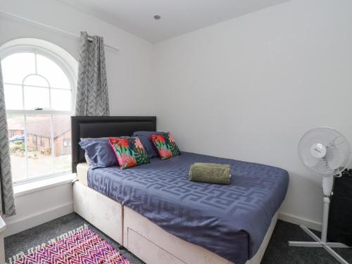 a bedroom with a bed with blue sheets and a window at The Old Station House in Withernsea