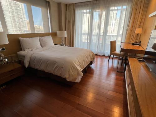 a hotel room with a bed and a desk and windows at The Sandalwood Beijing Marriott Executive Apartments in Beijing