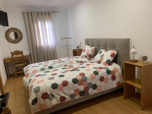 a bedroom with a bed with a comforter on it at Casa das Hortênsias in Cerdeira