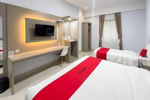 a hotel room with two beds and a desk with a tv at RedDoorz Syariah near Taman Kopi Gayo in Takengon