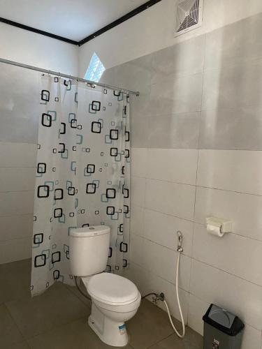 a bathroom with a toilet and a shower curtain at Akalanka Homestay in Gili Trawangan