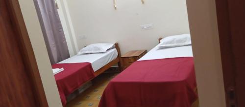 two beds in a small room with red and white sheets at Kodai Elegance in Kodaikānāl