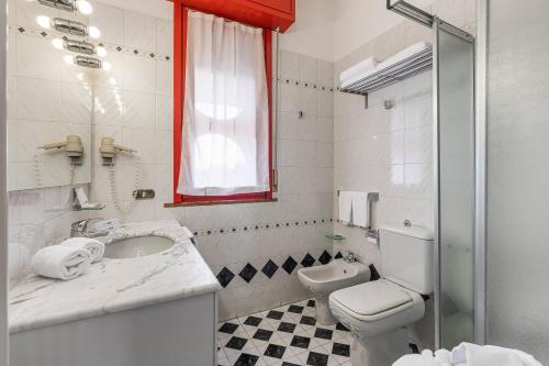 a white bathroom with a toilet and a sink at City Style Hotel Reggio Emilia in Reggio Emilia