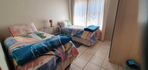 una habitación con dos camas y una ventana en Victoria Court 2, en Henties Bay