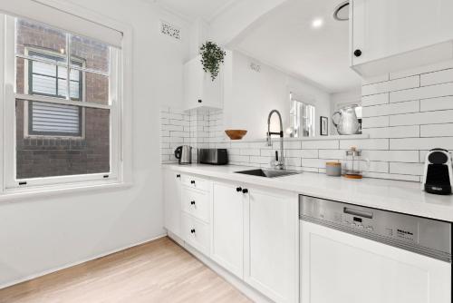 a white kitchen with a sink and a window at Perfect Holiday Home with Private Rooftop in Sydney