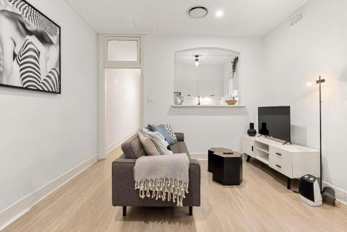 a white living room with a couch and a tv at Perfect Holiday Home with Private Rooftop in Sydney
