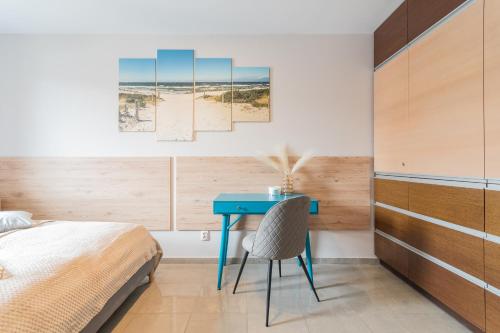 a bedroom with a blue desk and a bed at Apartamenty NCNK Baltic Park MEDIUM w Stegnie - 500 m do plaży in Stegna