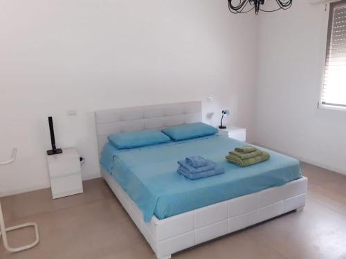 um quarto branco com uma cama com lençóis azuis em Casa di campagna pace e tranquillità em Brentanella
