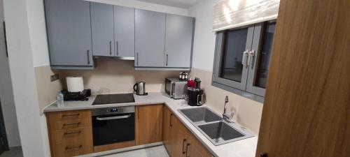 a small kitchen with white cabinets and a sink at Aegean Sunset in Agios Sostis