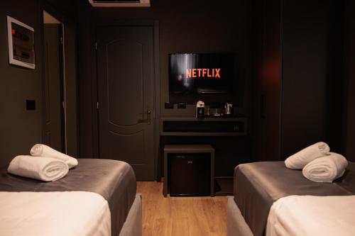 a room with two beds and a tv on the wall at Bel Ami Tirana in Tirana
