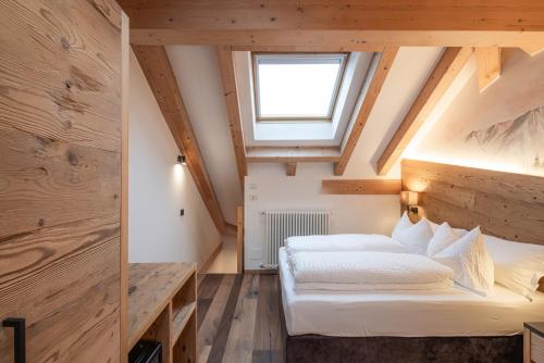 two beds in a attic room with a window at Hotel Bellavista in Cavalese